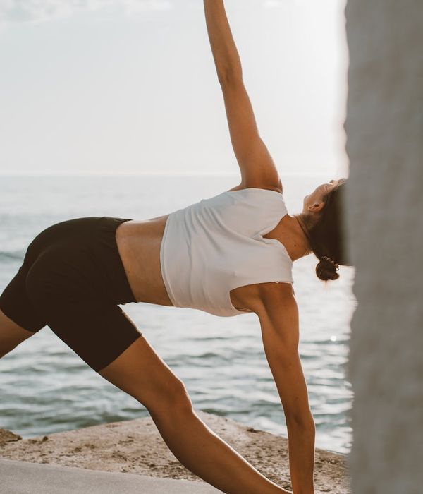 Person stretching peacefully outdoors during sunrise.